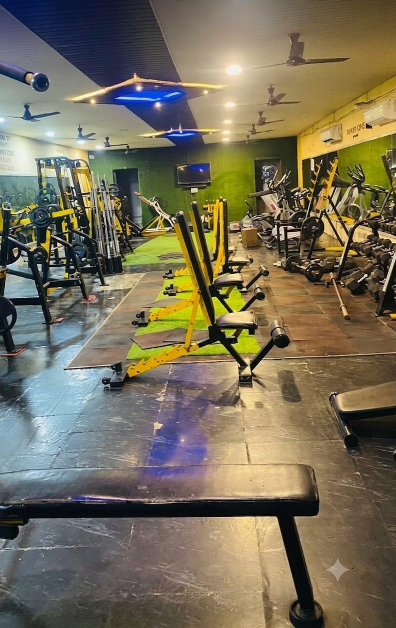 Weight bench and rows of yellow strength machines at Bhandari Gym